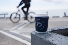 Eine Kaffeetasse mit einem Radfahrer im Hintergrund stockbild Eine Kaffeetasse mit einem Radfahrer im Hintergrund stockbild