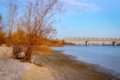 Eine lange Eisenbahnbrücke über dem Fluss Ansicht vom Ufer bei Sonnenuntergang Lizenzfreie Stockbilder Eine lange Eisenbahnbrücke über dem Fluss Ansicht vom Ufer bei Sonnenuntergang Lizenzfreie Stockbilder