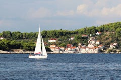 Eine moderne Kreuzfahrtsegeljacht mit einer Schaluppe-artigen Anlage Bermudas geht hinter die grüne Küste des Kroaten Riviera auf stockfotos Eine moderne Kreuzfahrtsegeljacht mit einer Schaluppe-artigen Anlage Bermudas geht hinter die grüne Küste des Kroaten Riviera auf stockfotos