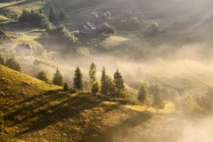 Eine nebelige Landschaft des schönen Herbstes mit einsamen Häusern und sonnigen Hügeln Ländliche Karpatenlandschaft auf Sonnenunt stockfotografie Eine nebelige Landschaft des schönen Herbstes mit einsamen Häusern und sonnigen Hügeln Ländliche Karpatenlandschaft auf Sonnenunt stockfotografie