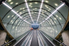 Eine Reinigungspersonalperson im orange Mantel auf Rolltreppe an der modernen, futuristischen Architekturu-bahnstation, gewölbte stockbilder Eine Reinigungspersonalperson im orange Mantel auf Rolltreppe an der modernen, futuristischen Architekturu-bahnstation, gewölbte stockbilder