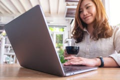 Eine schöne asiatische verwendende und auf Laptopberührungsfläche beim Trinken des Kaffees berührend Frau stockbild Eine schöne asiatische verwendende und auf Laptopberührungsfläche beim Trinken des Kaffees berührend Frau stockbild