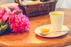 Eine Tasse Tee und Pfingstrosen, Honig, Löffelablagen auf der Untertasse, Holztisch, gemütliches Haus Stockfotografie Eine Tasse Tee und Pfingstrosen, Honig, Löffelablagen auf der Untertasse, Holztisch, gemütliches Haus Stockfotografie