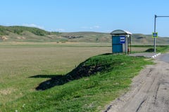 Einsame Bushaltestelle auf dem Hintergrund einer schönen Frühlingslandschaft, -felder, -wiesen, -wälder und -hügel Busverbindung lizenzfreies stockbild Einsame Bushaltestelle auf dem Hintergrund einer schönen Frühlingslandschaft, -felder, -wiesen, -wälder und -hügel Busverbindung lizenzfreies stockbild