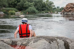 Einsamer Mann sitzt durch den Fluss in einer roten Weste lizenzfreie stockbilder Einsamer Mann sitzt durch den Fluss in einer roten Weste lizenzfreie stockbilder