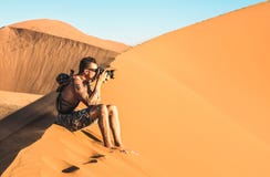 Einsamer Mannphotograph, der auf Sand an Düne 45 in Sossusvlei Namibia sitzt stockbild Einsamer Mannphotograph, der auf Sand an Düne 45 in Sossusvlei Namibia sitzt stockbild