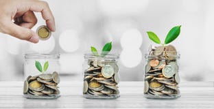 Einsparungsgeld, Bankwesen- und Investitionskonzepte, Hand, die Münze in Glasflaschen mit Betriebsdem glühen einsetzt stockfotografie Einsparungsgeld, Bankwesen- und Investitionskonzepte, Hand, die Münze in Glasflaschen mit Betriebsdem glühen einsetzt stockfotografie