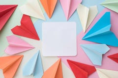 El aeroplano de papel colorido y la nota blanca en blanco empapelan el cojín en fondo en colores pastel colorido foto de archivo libre de regalías El aeroplano de papel colorido y la nota blanca en blanco empapelan el cojín en fondo en colores pastel colorido foto de archivo libre de regalías