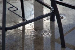 El agua gotea debajo de los muebles en un patio después de que un chubasco de la lluvia como el sol se rompa a través fotografía de archivo libre de regalías El agua gotea debajo de los muebles en un patio después de que un chubasco de la lluvia como el sol se rompa a través fotografía de archivo libre de regalías