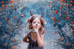 El alcohol del bosque bajo la forma de niño en un vestido marrón claro, un ciervo del bebé lleva juguetónamente en el bosque, fotos de archivo El alcohol del bosque bajo la forma de niño en un vestido marrón claro, un ciervo del bebé lleva juguetónamente en el bosque, fotos de archivo