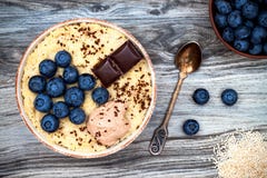 El amaranto del gluten y el desayuno libres de las gachas de avena de la quinoa ruedan con los arándanos y el chocolate sobre fon fotos de archivo El amaranto del gluten y el desayuno libres de las gachas de avena de la quinoa ruedan con los arándanos y el chocolate sobre fon fotos de archivo