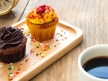 El amarillo y las magdalenas del chocolate pusieron una placa de madera esférica Al lado de la magdalena tenga taza del cactus y Foto de archivo libre de regalías El amarillo y las magdalenas del chocolate pusieron una placa de madera esférica Al lado de la magdalena tenga taza del cactus y Foto de archivo libre de regalías