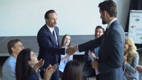 El apretón de manos de dos hombres de negocios durante la reunión Partners el concepto del acuerdo, Boss With Team Of Businesspeo almacen de metraje de vídeo El apretón de manos de dos hombres de negocios durante la reunión Partners el concepto del acuerdo, Boss With Team Of Businesspeo almacen de metraje de vídeo