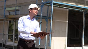 El arquitecto examina la construcci?n fuera de hablar en el tel?fono El arquitecto examina la construcci?n fuera de hablar en el tel?fono