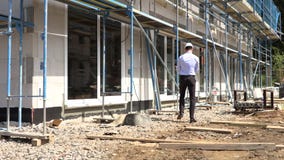 El arquitecto examina la construcci?n fuera de hablar en el tel?fono El arquitecto examina la construcci?n fuera de hablar en el tel?fono