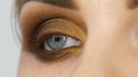 El artista de maquillaje principal profesional aplica el sombreador de ojos beige con el finger en el ojo modelo en el cierre del almacen de video El artista de maquillaje principal profesional aplica el sombreador de ojos beige con el finger en el ojo modelo en el cierre del almacen de video