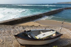 El barco de rowing de Cornualles de la ensenada de Sennon y la pared del puerto con el mar azul y el blanco agita imagenes de archivo El barco de rowing de Cornualles de la ensenada de Sennon y la pared del puerto con el mar azul y el blanco agita imagenes de archivo