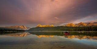 El barco en un lago como la luz de la mañana golpea los tops de la alta montaña Foto de archivo El barco en un lago como la luz de la mañana golpea los tops de la alta montaña Foto de archivo