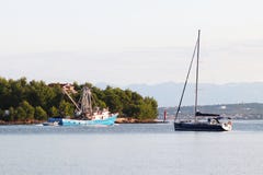 El barco pesquero para las devoluciones de la extracción del calamar en la navegación de la madrugada más allá del yate verde de fotografía de archivo El barco pesquero para las devoluciones de la extracción del calamar en la navegación de la madrugada más allá del yate verde de fotografía de archivo