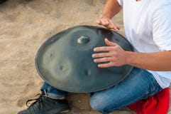 El batería en la acción individuo que se sienta en la playa y el jugar handpan o la caída de la arena La caída es tambor étnico t foto de archivo El batería en la acción individuo que se sienta en la playa y el jugar handpan o la caída de la arena La caída es tambor étnico t foto de archivo