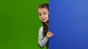 El bebé mira hacia fuera de detrás un tablero vacío Pantalla verde almacen de video El bebé mira hacia fuera de detrás un tablero vacío Pantalla verde almacen de video