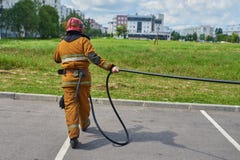 El bombero de sexo masculino tira de la manguera fotos de archivo libres de regalías El bombero de sexo masculino tira de la manguera fotos de archivo libres de regalías