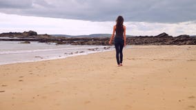 El caminar moreno hermoso a lo largo del agua por la playa almacen de metraje de vídeo El caminar moreno hermoso a lo largo del agua por la playa almacen de metraje de vídeo