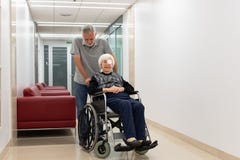 El centro envejeció al hombre que ayudaba y que llevaba los ancianos 95 años de la mujer que se sentaba en la silla de ruedas foto de archivo El centro envejeció al hombre que ayudaba y que llevaba los ancianos 95 años de la mujer que se sentaba en la silla de ruedas foto de archivo