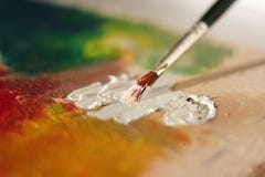 El cepillo manchado mezcla la pintura de aceite blanco en una paleta fotos de archivo libres de regalías El cepillo manchado mezcla la pintura de aceite blanco en una paleta fotos de archivo libres de regalías