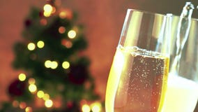 El champán de colada en las flautas con las burbujas de oro con el árbol de navidad borroso centelleo abstracto de oro enciende e almacen de video El champán de colada en las flautas con las burbujas de oro con el árbol de navidad borroso centelleo abstracto de oro enciende e almacen de video