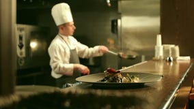 El cocinero de sexo masculino está cocinando Flambe en cocina del restaurante El cocinero de sexo masculino está cocinando Flambe en cocina del restaurante
