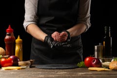 El cocinero prepara la chuleta con la carne picada fresca, sosteni?ndose bajo la forma de coraz?n, los ingredientes en el fondo, fotografía de archivo libre de regalías El cocinero prepara la chuleta con la carne picada fresca, sosteni?ndose bajo la forma de coraz?n, los ingredientes en el fondo, fotografía de archivo libre de regalías