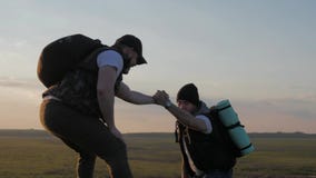 El compa?ero de equipo de ayuda del escalador subir, el hombre con la mochila alcanz? hacia fuera una mano amiga a su amigo Amigo metrajes El compa?ero de equipo de ayuda del escalador subir, el hombre con la mochila alcanz? hacia fuera una mano amiga a su amigo Amigo metrajes
