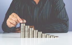 El concepto del dinero del ahorro y la mano del hombre de negocios que ponen el dinero acuñan foto de archivo libre de regalías El concepto del dinero del ahorro y la mano del hombre de negocios que ponen el dinero acuñan foto de archivo libre de regalías
