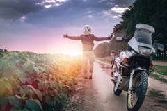 El conductor de motocicleta se coloca con sus brazos extendidos para una reunión de aventuras en el tiempo de la puesta del sol foto de archivo El conductor de motocicleta se coloca con sus brazos extendidos para una reunión de aventuras en el tiempo de la puesta del sol foto de archivo