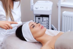 El cosmetologist hace la terapia de Microcurrent del procedimiento de la piel facial de una mujer hermosa, joven imagen de archivo El cosmetologist hace la terapia de Microcurrent del procedimiento de la piel facial de una mujer hermosa, joven imagen de archivo
