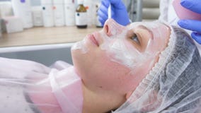 El cosmetólogo pone una máscara blanca en la cara de la mujer con un cepillo Manos de un cosmetologist en guantes de goma azules metrajes El cosmetólogo pone una máscara blanca en la cara de la mujer con un cepillo Manos de un cosmetologist en guantes de goma azules metrajes