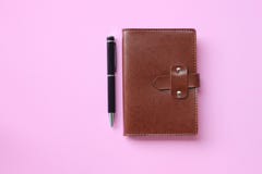El cuaderno y la pluma se colocan en un piso rosado y tienen espacio de la copia fotografía de archivo El cuaderno y la pluma se colocan en un piso rosado y tienen espacio de la copia fotografía de archivo