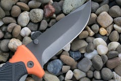 El cuchillo de la supervivencia en los guijarros oscila piedras fotografía de archivo libre de regalías El cuchillo de la supervivencia en los guijarros oscila piedras fotografía de archivo libre de regalías