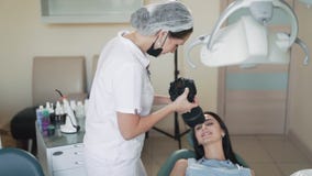 El dentista toma la foto de la sonrisa paciente después del tratamiento dental, cámara lenta almacen de metraje de vídeo El dentista toma la foto de la sonrisa paciente después del tratamiento dental, cámara lenta almacen de metraje de vídeo