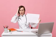 El doctor de sexo femenino se sienta en los trabajos de escritorio en el ordenador con el ekg médico del corazón del documento en imagen de archivo El doctor de sexo femenino se sienta en los trabajos de escritorio en el ordenador con el ekg médico del corazón del documento en imagen de archivo