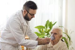 El doctor sostiene el inhalador la cara de una mujer mayor foto de archivo libre de regalías El doctor sostiene el inhalador la cara de una mujer mayor foto de archivo libre de regalías