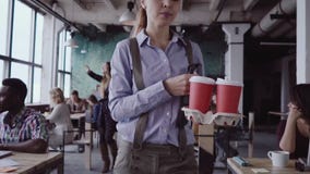 El encargado de sexo femenino moreno viene a la oficina moderna en el trabajo La mujer joven saluda con los colegas, trae el café metrajes El encargado de sexo femenino moreno viene a la oficina moderna en el trabajo La mujer joven saluda con los colegas, trae el café metrajes