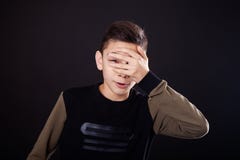 El fall, el muchacho se cierra la mano Liuo, espías Escondite, mirando furtivamente El individuo, adolescente en un fondo negro, imagenes de archivo El fall, el muchacho se cierra la mano Liuo, espías Escondite, mirando furtivamente El individuo, adolescente en un fondo negro, imagenes de archivo