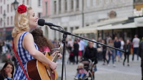 El funcionamiento de la calle, muchacha con una flor en su pelo canta y toca la guitarra en el micrófono El funcionamiento de la calle, muchacha con una flor en su pelo canta y toca la guitarra en el micrófono