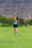 El golfista de sexo femenino golpea la pelota de golf Imagen de archivo libre de regalías El golfista de sexo femenino golpea la pelota de golf Imagen de archivo libre de regalías