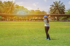 El golfista largo asiático de la mujer del pelo golpeó golf en la maldición verde del golf fotografía de archivo El golfista largo asiático de la mujer del pelo golpeó golf en la maldición verde del golf fotografía de archivo