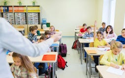 El grupo de escuela embroma el aumento de las manos en sala de clase imágenes de archivo libres de regalías El grupo de escuela embroma el aumento de las manos en sala de clase imágenes de archivo libres de regalías