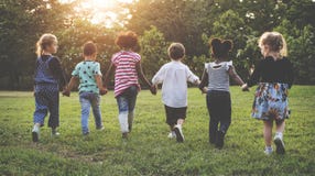 El grupo de guardería embroma a los amigos que llevan a cabo las manos que juegan en el parque El grupo de guardería embroma a los amigos que llevan a cabo las manos que juegan en el parque