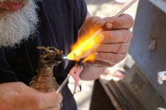 El hombre barbudo blanco cosechado crea a la hada de cristal usando lampworking - las barras de cristal de fusión con una antorch fotografía de archivo El hombre barbudo blanco cosechado crea a la hada de cristal usando lampworking - las barras de cristal de fusión con una antorch fotografía de archivo